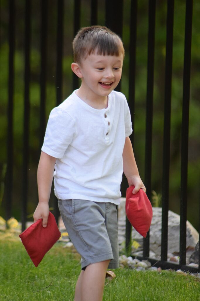 Child plays with red cornhole bean bags